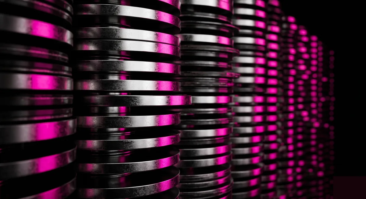 Photorealistic macro of stacked storage drive platters lit by hot-pink rim light receding into black, representing near-zero-cost storage that removes the friction against hoarding data