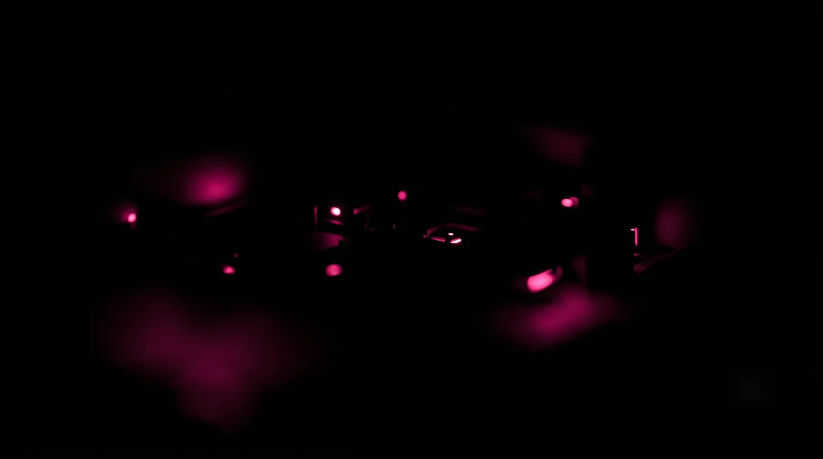 Faint scattered hot-pink glows half-hidden in deep black, shadow AI tools being used quietly out of the organization's sight
