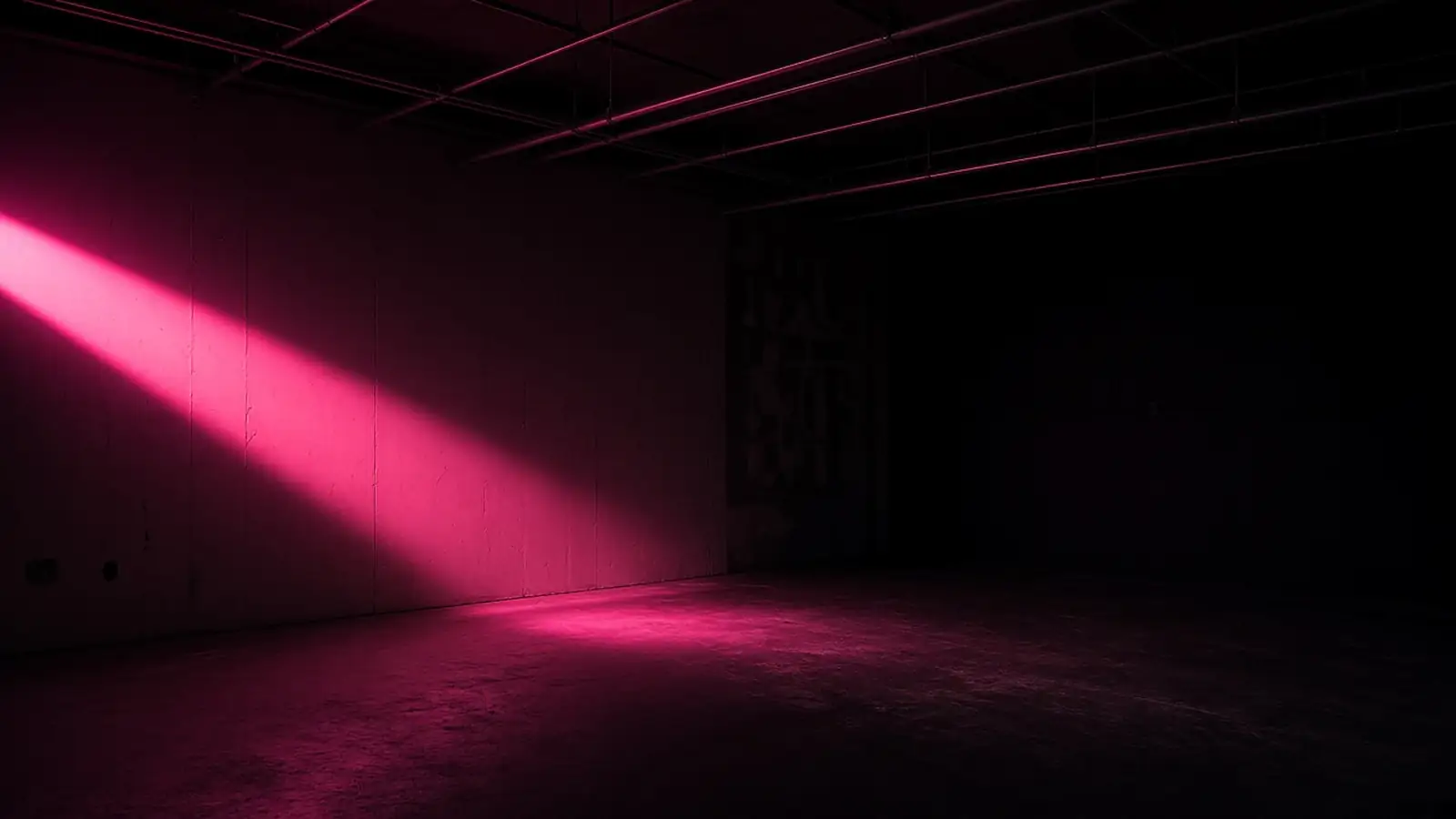 An empty commercial space at night with a single hot pink light cutting across bare walls and conduit, opening a business location in Shrewsbury