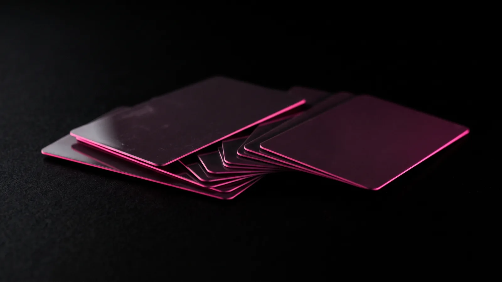 A fan of blank plastic gift cards on black with a hot pink edge light, the boss gift card request common in smishing