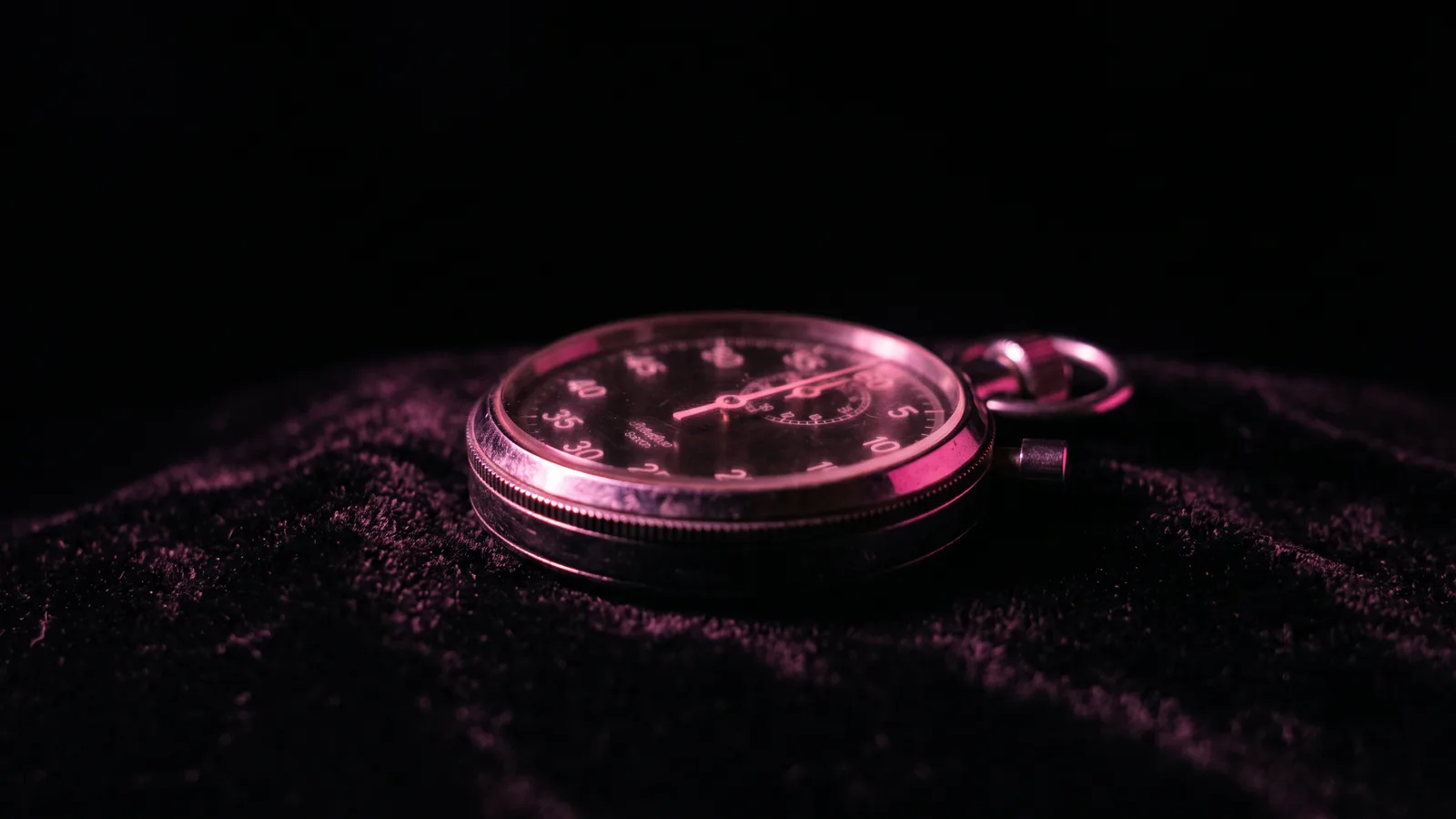 A mechanical stopwatch on black velvet with its hand lit hot pink just past the ten second mark, how long most security awareness training sessions actually last