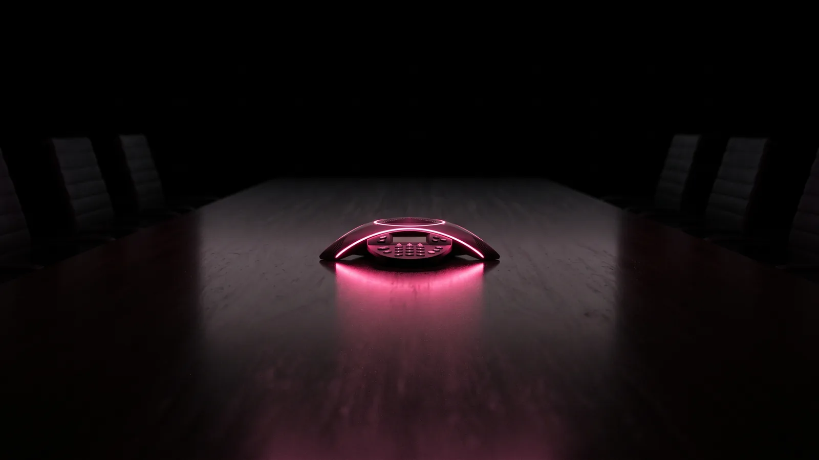 A conference speakerphone on an empty boardroom table glowing hot pink in the dark, the meeting setting used in deepfake vishing fraud